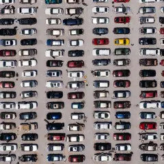 Wielki parking pełen europejskich marek samochodów, uporządkowanych w rzędach.