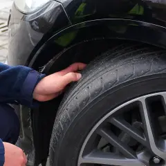 Dłoń sprawdza stan opony, która może być przyczyną drgań na kierownicy przy 120 km/h.