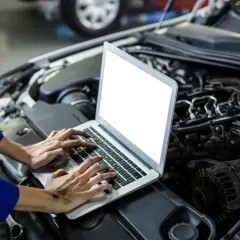 Mechanik diagnozuje szarpanie na niskich obrotach benzyna, analizując dane z komputera pod maską samochodu.