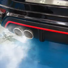 Dym z podwójnej końcówki wydechu czarnego samochodu, sugerujący, dlaczego diesel kopci na czarno.