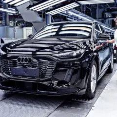 Czarny Audi na linii produkcyjnej. Pracownica sprawdza jakość pojazdu, który opuszcza fabrykę w Niemczech.