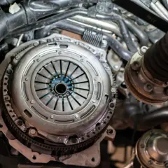 Mechanik pracuje nad grawitacyjnym odpowietrzaniem sprzęgła w samochodzie. Widoczny jest mechanizm sprzęgła i elementy silnika.