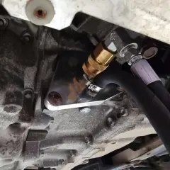 Metalowy adapter z szybkozłączką do dynamicznej wymiany oleju w skrzyni biegów, podłączony do węży.