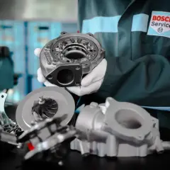 Mechanik w białych rękawiczkach prezentuje części turbosprężarki. Zwróć uwagę na uszkodzony wąż turbiny objawy, gdy widzisz takie elementy.
