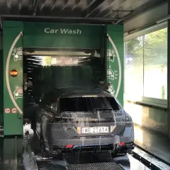 Czarnym autem wjeżdżamy do myjni automatycznej. Piana i szczotki skutecznie usuwają brud, pokazując, czym umyć auto.