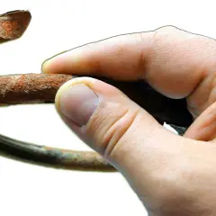 Dłoń trzyma zardzewiały fragment sprężyny, symbolizujący potrzebę wymiany sprężyn przód.