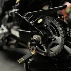 Zbliżenie na tylne koło motocykla z widocznym łańcuchem i zębatką, gotowe do czyszczenia łańcucha motocyklowego.