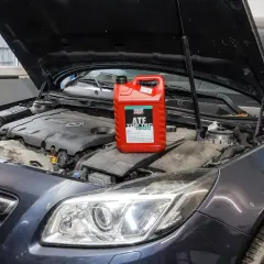 Czerwony kanister z płynem do automatycznych skrzyń biegów Liqui Moly ATF Top Tec 1800 na silniku samochodu.