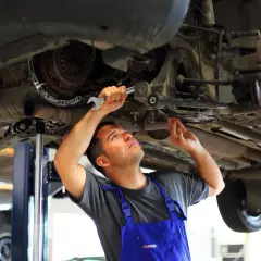 Mechanik wykonuje wymianę tulei wahacza domowym sposobem, używając klucza do precyzyjnej pracy.