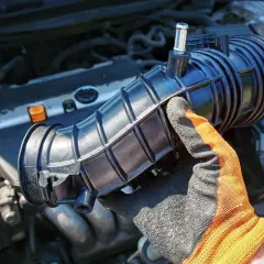 Ręka w rękawicy trzyma element układu dolotowego silnika 1.8T. Może to być związane z objawami zatkanej odmy.