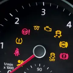 Deska rozdzielcza Peugeot 208 z zapalonymi kontrolkami: ABS, ESP, poduszki powietrzne, ciśnienie w oponach, hamulec ręczny.