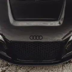 Maskownica i maska z włókna węglowego na czarnym aucie sportowym Audi.