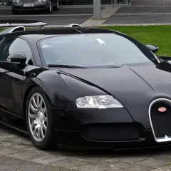 Czarny Bugatti Veyron, symbol luksusu i mocy, prezentuje się na tle innych drogich marek samochodów.