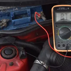Sprawdzanie akumulatora multimetrem, by dowiedzieć się, jak odpalić auto z rozładowanym akumulatorem. Wynik 8.71V wskazuje na problem.