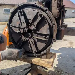 Mechanik w rękawiczkach reguluje mechanizm sprzęgła, przygotowując traktor do pracy.
