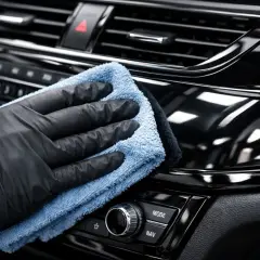Rękawiczka i ściereczka z mikrofibry czyszczą błyszczące piano black we wnętrzu samochodu.