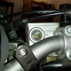 Zbiorniczek płynu hamulcowego motocykla z widocznym poziomem płynu.