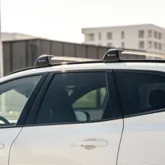 Biały SUV z zamontowanymi relingami dachowymi Yakima. Różne rodzaje relingów dachowych pozwalają na przewożenie bagażu.