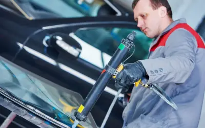 Mechanik aplikuje uszczelniacz na szybę samochodu. Pytanie: czym smarować uszczelki w aucie? Odpowiedź: specjalistycznym preparatem.