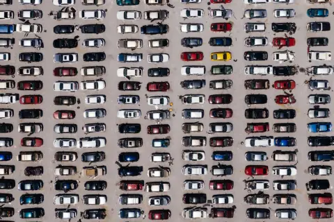 Wielki parking pełen europejskich marek samochodów, uporządkowanych w rzędach.