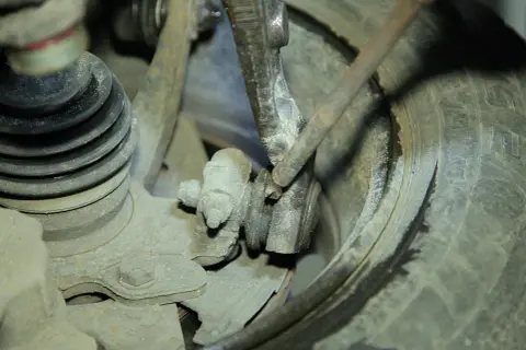 Mechanik bada przyczynę chrobotania przy skręcaniu kierownicą, sprawdzając zużyte elementy zawieszenia i przegub.