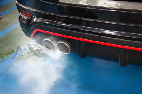 Dym z podwójnej końcówki wydechu czarnego samochodu, sugerujący, dlaczego diesel kopci na czarno.