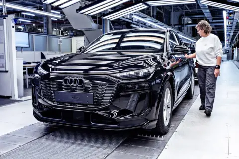 Czarny Audi na linii produkcyjnej. Pracownica sprawdza jakość pojazdu, który opuszcza fabrykę w Niemczech.