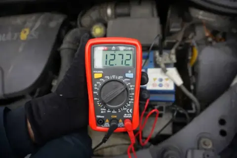 Multimetr pokazuje 12.72V, co może oznaczać, że akumulator nie trzyma napięcia. Sprawdzanie stanu baterii w samochodzie.