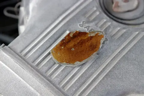 Fragment metalowej obudowy silnika z widocznym, lekko przytartym elementem o brązowym zabarwieniu.