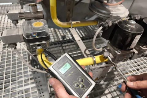 Technik przeprowadza sprawdzenie szczelności instalacji gazowej za pomocą detektora.