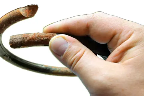 Dłoń trzyma zardzewiały fragment sprężyny, symbolizujący potrzebę wymiany sprężyn przód.