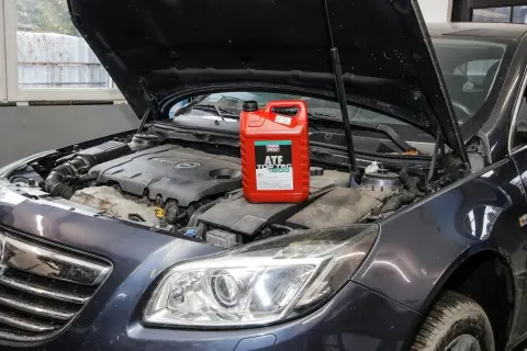 Czerwony kanister z płynem do automatycznych skrzyń biegów Liqui Moly ATF Top Tec 1800 na silniku samochodu.