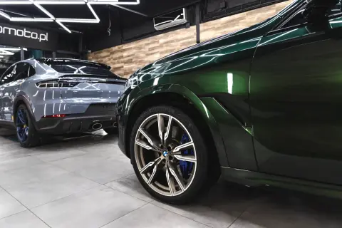 Zielony BMW i szary Porsche w garażu. To praca detailera, który dba o każdy detal.