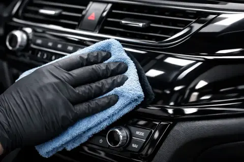 Rękawiczka i ściereczka z mikrofibry czyszczą błyszczące piano black we wnętrzu samochodu.