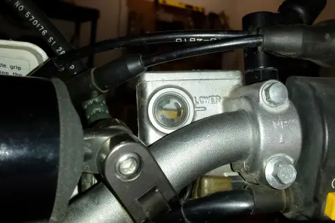 Zbiorniczek płynu hamulcowego motocykla z widocznym poziomem płynu.