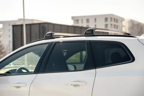 Biały SUV z zamontowanymi relingami dachowymi Yakima. Różne rodzaje relingów dachowych pozwalają na przewożenie bagażu.