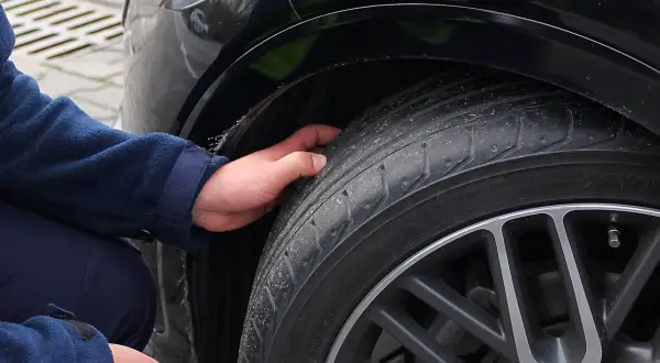 Dłoń sprawdza stan opony, która może być przyczyną drgań na kierownicy przy 120 km/h.