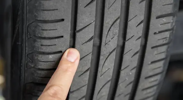 Palec wskazujący na bieżniku opony, uwidaczniający drobne mikropęknięcia.