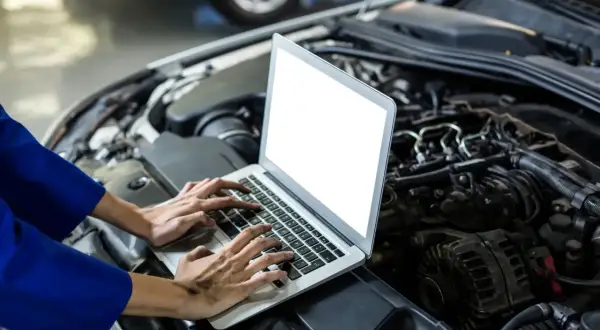 Mechanik diagnozuje szarpanie na niskich obrotach benzyna, analizując dane z komputera pod maską samochodu.
