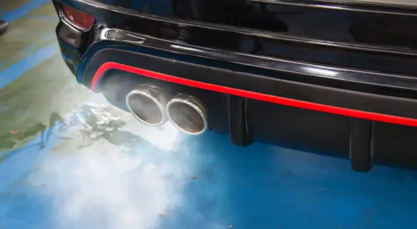 Dym z podwójnej końcówki wydechu czarnego samochodu, sugerujący, dlaczego diesel kopci na czarno.