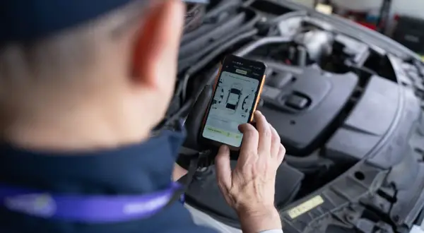 Mechanik sprawdza kody błędów DTC Renault na telefonie, analizując raport z pomiarów lakieru i szczelin.