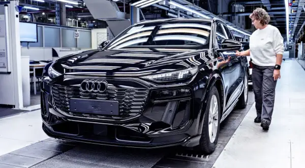 Czarny Audi na linii produkcyjnej. Pracownica sprawdza jakość pojazdu, który opuszcza fabrykę w Niemczech.