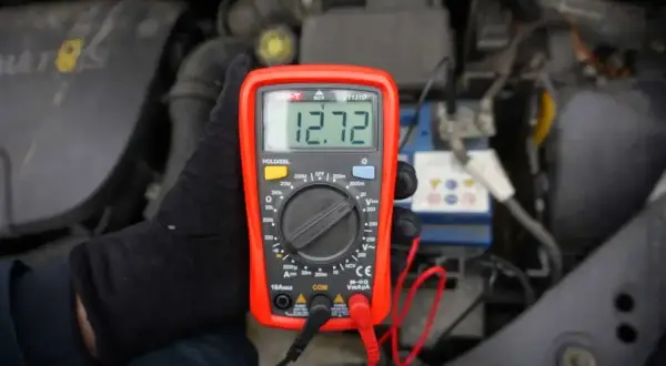 Multimetr pokazuje 12.72V, co może oznaczać, że akumulator nie trzyma napięcia. Sprawdzanie stanu baterii w samochodzie.