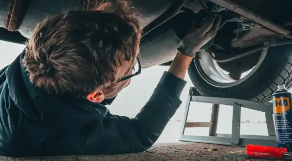 Mechanik bada podwozie auta, szukając przyczyn problemów z elektrozaworem skrzyni biegów. Objawy mogą być różne.