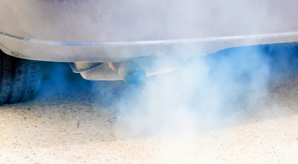 Niebieski dym z wydechu diesel, który wydobywa się z rury wydechowej samochodu, tworzy chmurę zanieczyszczeń.