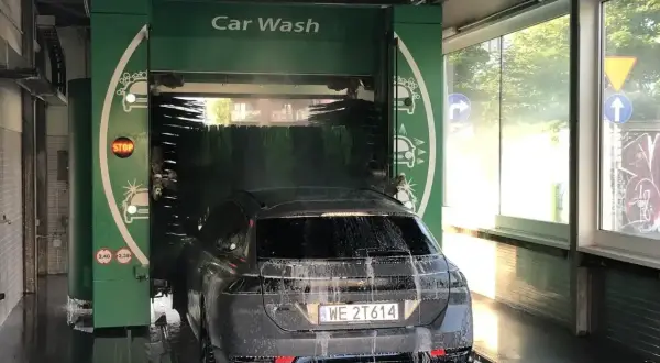 Czarnym autem wjeżdżamy do myjni automatycznej. Piana i szczotki skutecznie usuwają brud, pokazując, czym umyć auto.