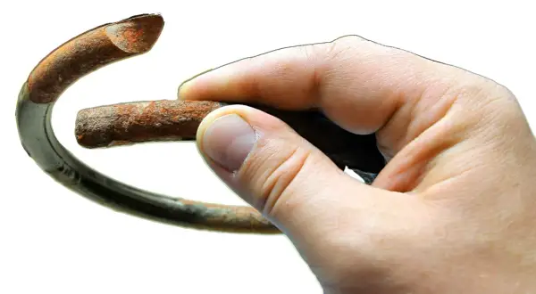 Dłoń trzyma zardzewiały fragment sprężyny, symbolizujący potrzebę wymiany sprężyn przód.