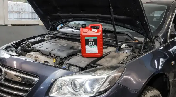 Czerwony kanister z płynem do automatycznych skrzyń biegów Liqui Moly ATF Top Tec 1800 na silniku samochodu.