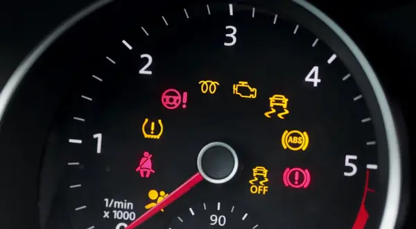 Deska rozdzielcza Peugeot 208 z zapalonymi kontrolkami: ABS, ESP, poduszki powietrzne, ciśnienie w oponach, hamulec ręczny.