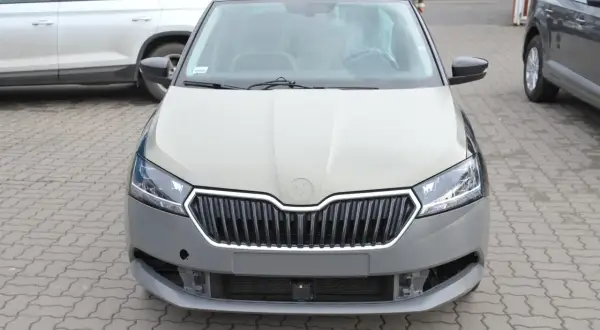 Szara maska samochodu Skoda czeka na malowanie. Widać kratkę grilla i reflektory.